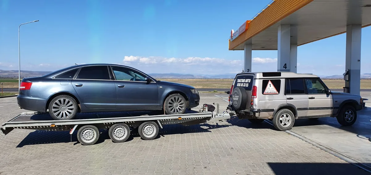 Audi albastru pe remorca-platformă, oprit la o benzinărie